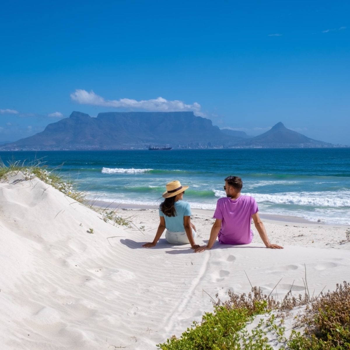 Bloubergstrand Cape Town South Africa on a bright summer day, Blouberg beach, withe powder sand and blue ocean. couple on the beach, men and woman chilling on the beach